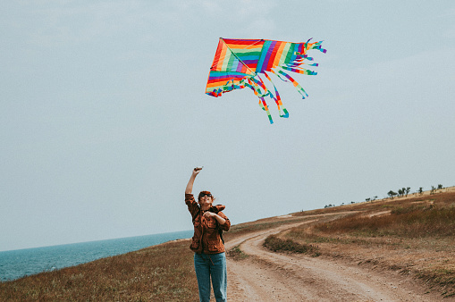 A young woman flies a kite on the seashore. The concept of freedom, travel, vacation