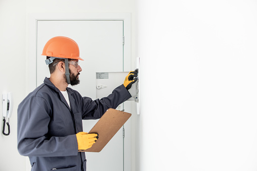 Electrician turning off circuit breakers to safely start work