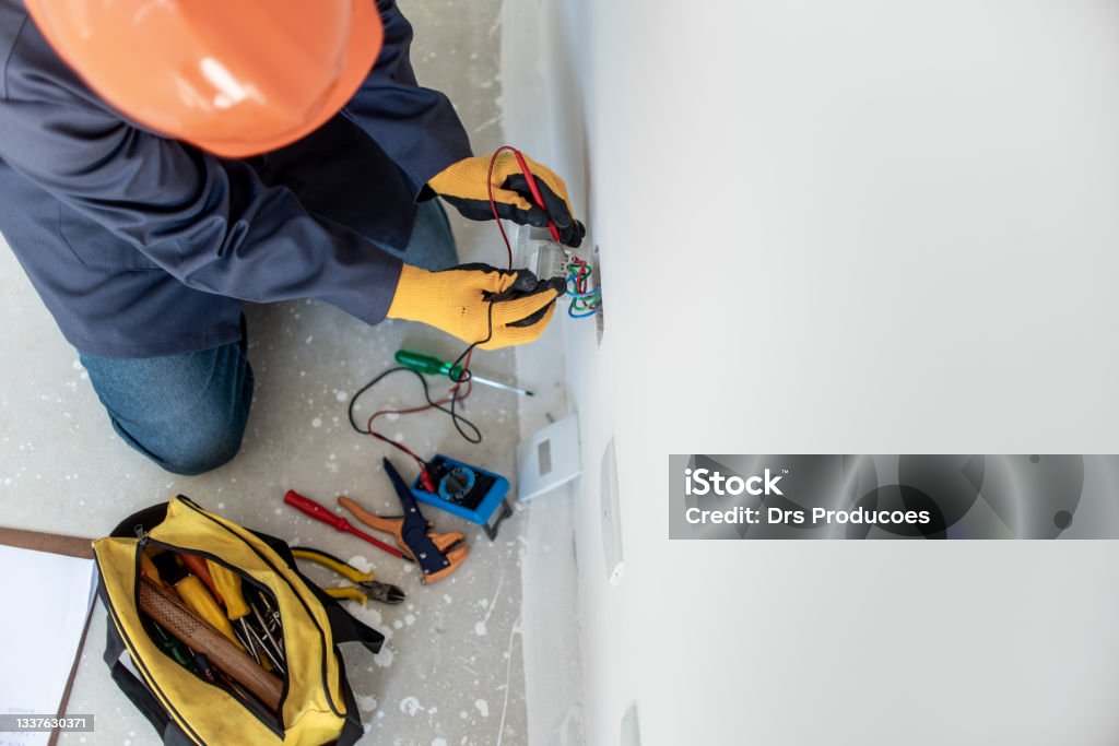 Man testing electricity with multimeter Man testing electricity with multimeter using safety equipment Electrician Stock Photo