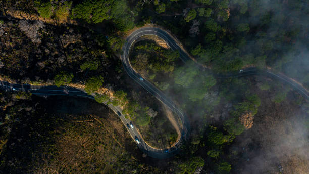 High angle shot of cars travelling on a road through a mountainous area Winding through the forest 4k resolution stock pictures, royalty-free photos & images