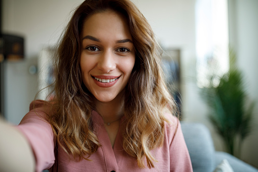 Smiling confident young woman having online conference from home office