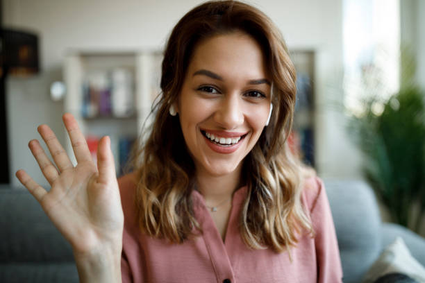 istock Young smiling woman with bluetooth headphones waving talking on webcam 1337642322
