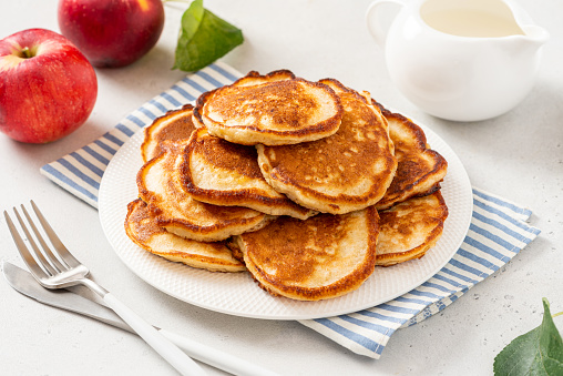 Homemade apple pancakes in a white plate on a gray concrete background. Tasty breakfast