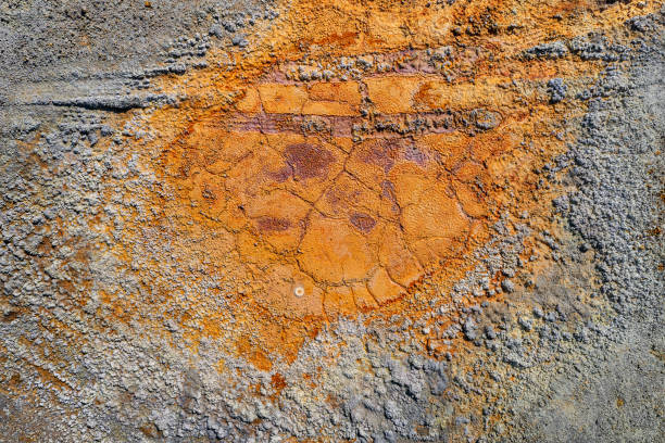 Dried rusty pool with tire tracks and rough grey contaminated land texture from abandoned pyrite mine
