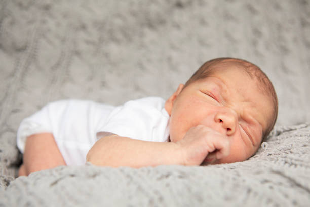 newborn sleeping and sucking thumb - thumb sucking cute small lying down imagens e fotografias de stock