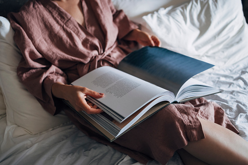 Close up photo of female hands holding a book in the morning at home