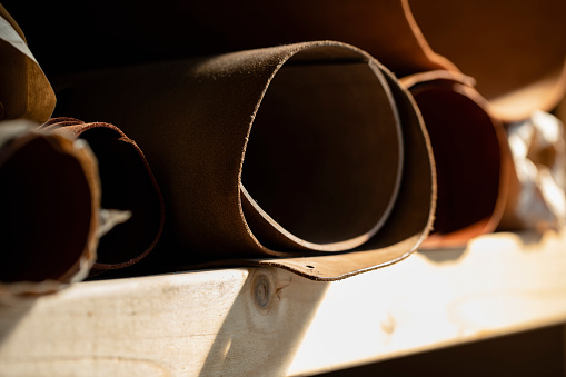 Rolled men's leather belt with metal buckle on wooden desktop