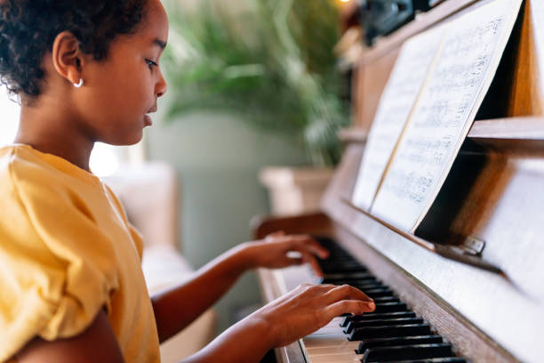 musikalische ausbildung. glückliches schwarzes mädchen, das klavier spielt - practicing piano child playing stock-fotos und bilder