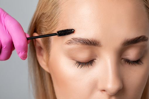 El maquillador peina y se arranca las cejas después de teñirse en un salón de belleza. Maquillaje profesional y cosmetología para el cuidado de la piel. photo