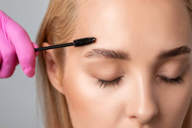 Makeup artist combs  and plucks eyebrows after dyeing in a beauty salon.Professional makeup and cosmetology skin care. Makeup artist combs  and plucks eyebrows after dyeing in a beauty salon.Professional makeup and cosmetology skin care. eyebrow photos stock pictures, royalty-free photos & images