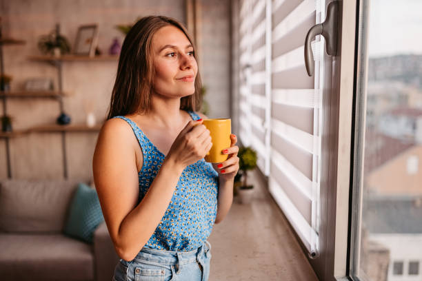 istock Woman is looking through the window and drinking coffee 1337654367