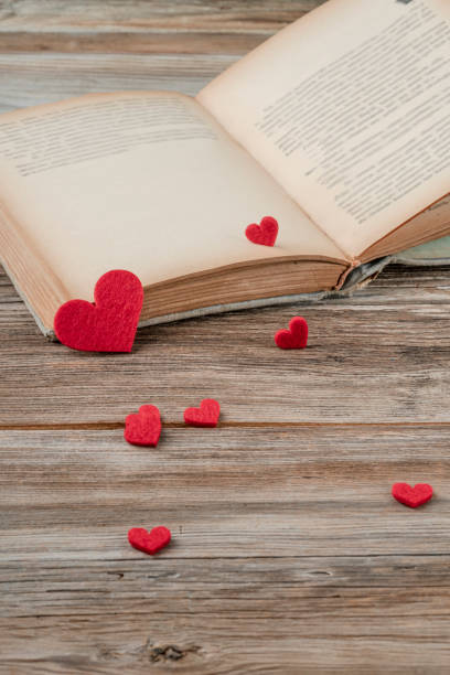 an old book opened on a wooden table decorated with red hearts valentines day concept with an old book opened on a wooden table decorated with red hearts book heart shape valentines day copy space stock pictures, royalty-free photos & images