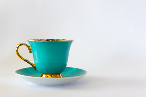 Traditional oriental Chinese coffee in vintage mug and saucer on wooden table in soft focus setting with ambient light