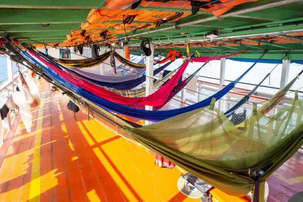 Photo of Colorful hammocks on Amazon Rainforest wooden boat in sunny summer day. Alter do Chão, Para, Brazil. Concept of nature, conservation, environment, ecology, vacation, tourism, travel.