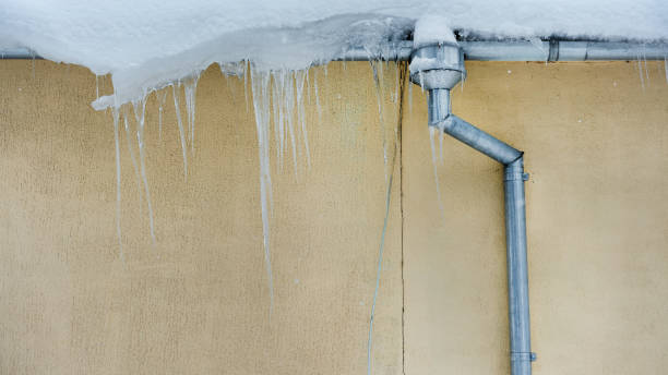 istock Steel drainpipe under snowdrift and icicles hanging on building roof 1337659239
