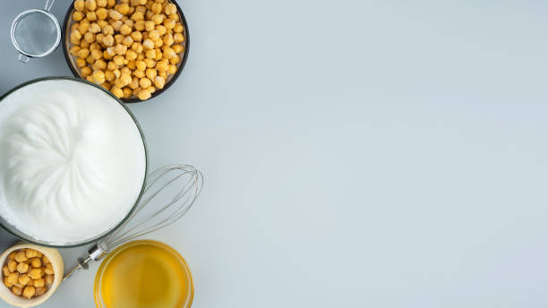 istock Chickpea aquafaba. Egg replacement. Vegan cooking concept. whipped chickpeas liquid in glass bowl. chickpea in a ceramic plate. whisk. gray isolated background. Top view. Copy space. Banner. 1337661954