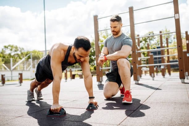 istock Fitness instructor with athlete on outdoor strength training doing push ups 1337670433