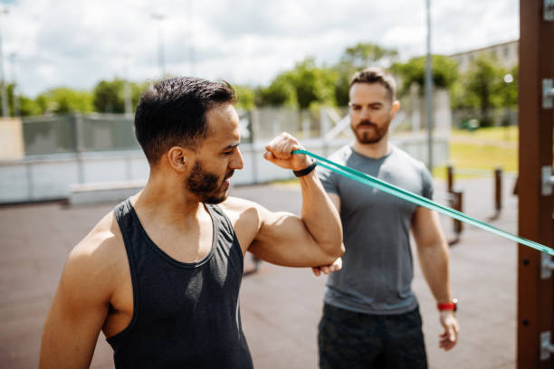 istock Fitness instructor with athlete, workout with rubbers for biceps flexibility 1337670497
