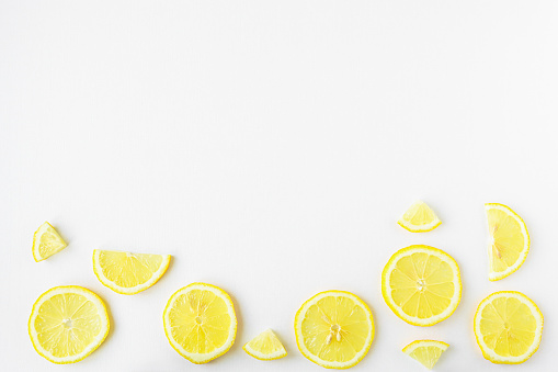 Fruit background with lemon slices top view. Sliced yellow fruit on a white wooden table.