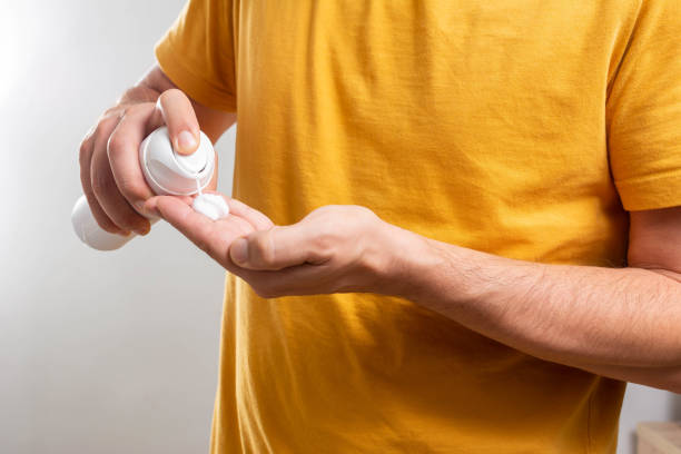 istock Unrecognizable man applying shaving foam from bottle onto his hand, white background. 1337672976