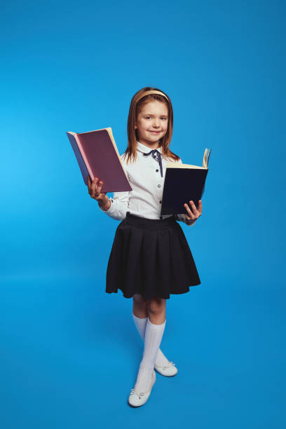 istock Schoolgirl learns information from textbook, poses over blue background 1337679732