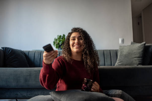 woman watching television - changing channels imagens e fotografias de stock