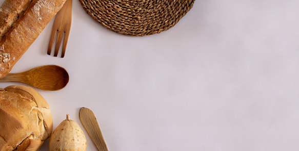 Rural bread loaf with pumpkin and wooden fork and ladle with wicker texture on white background. Top view. Flat lay. Copy space.