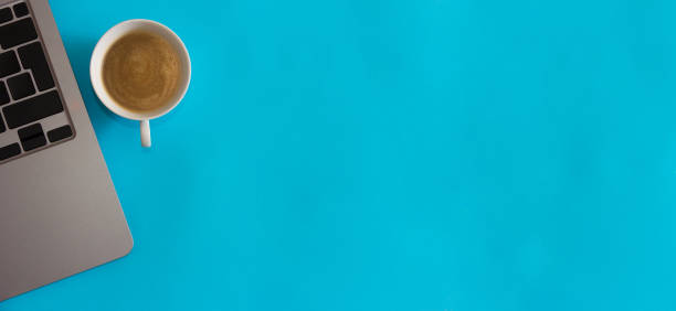 istock Laptop computer with coffee cup on blue background. Home office concept. Top view. Flat lay. Copy space. 1337684856