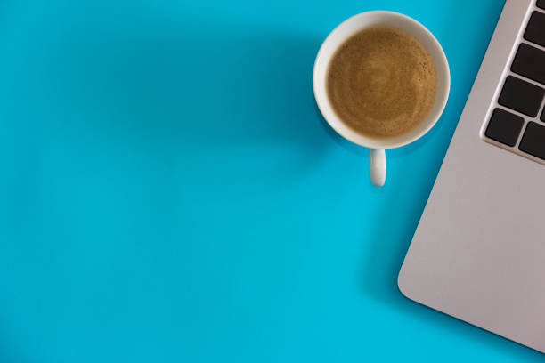 istock Laptop computer with coffee cup on blue background. Home office concept. Top view. Flat lay. Copy space. 1337684874
