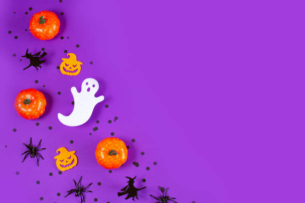 istock Halloween frame with pumpkins, ghost and spiders on purple Background. 1337685860