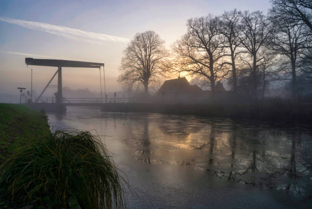 Bridge over a frozen and misty Overijsselsch Canal near the Dutch village Heeten