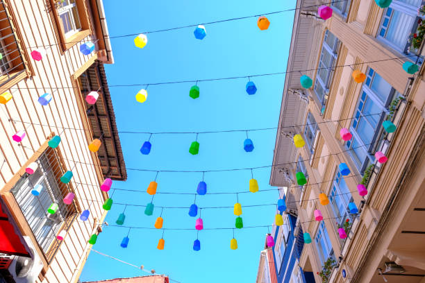 istock colorful light bulbs and lamps hanging between buildings under blue sky 1337696764