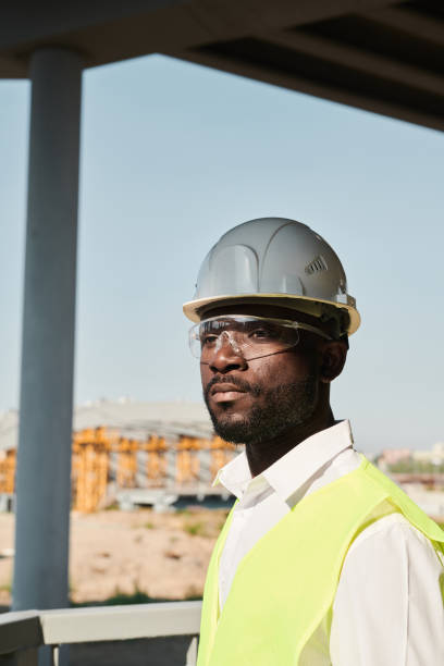 istock Black building worker standing on construction site without walls, unfinished block of apartments 1337699110