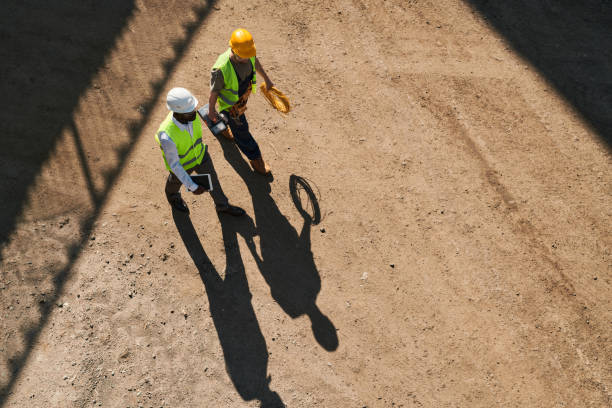 istock Contemplative modern constructors in safety vests and hardhats working on new house and discussing building process 1337699839