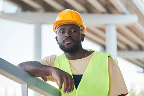 istock Portrait of smiling construction worker wearing hardhat while posing against concrete wall, copy space 1337699856