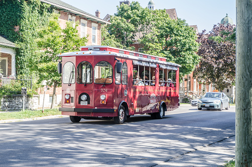 Trolley bus with tourists passing on street of Kingston during summer day