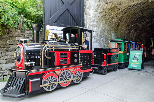 Small tourist train getting out of Canada first railway tunnel in Brockville during summer day