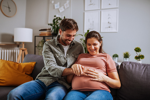 Married couple at home having fun with daughters. Woman is in late pregnancy