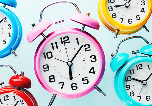 Assorted Collection of Colorful Alarm Clocks Each Showing a Different Time