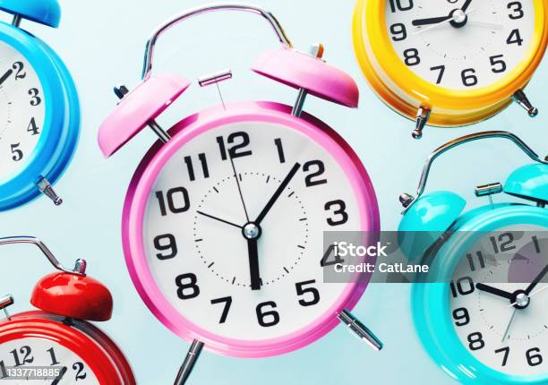 Assorted Collection Of Colorful Alarm Clocks Each Showing A Different Time Stock Photo - Download Image Now