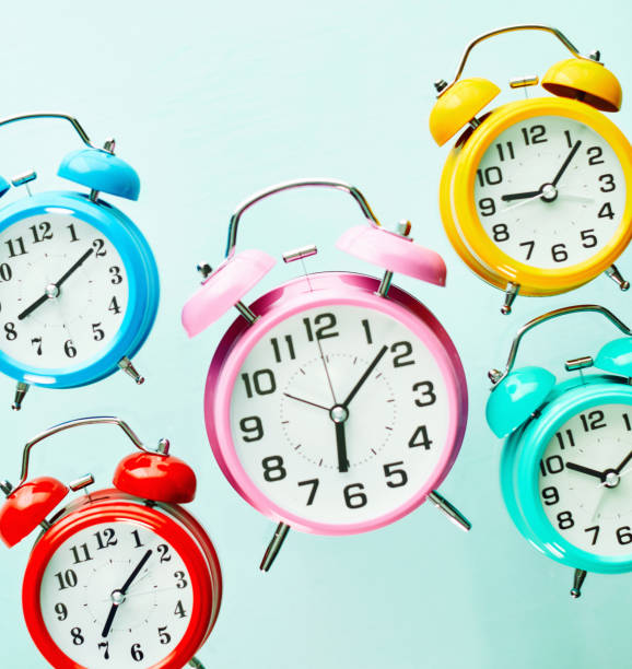 istock Assorted Collection of Colorful Alarm Clocks Each Showing a Different Time 1337718890