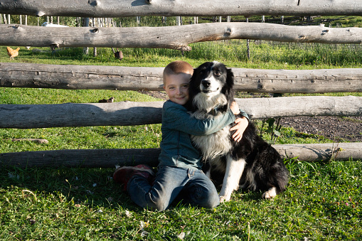 Little boy embracing his Cow dog on a farm in Southwest Colorado near Telluride, Schmid family Ranch
