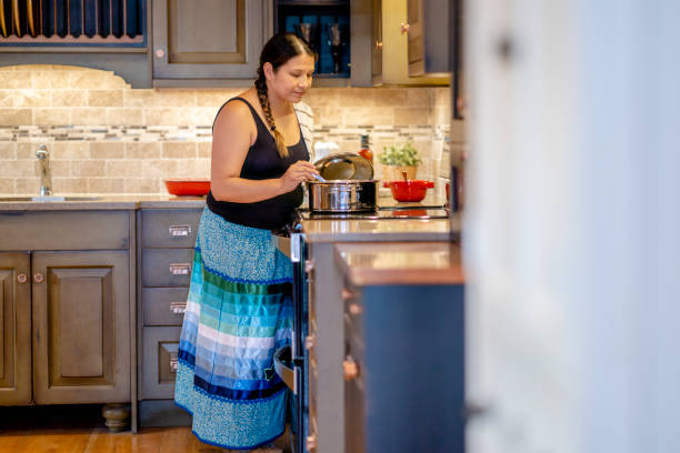 jeune femme autochtone cuisinant à la maison - native habitat photos et images de collection