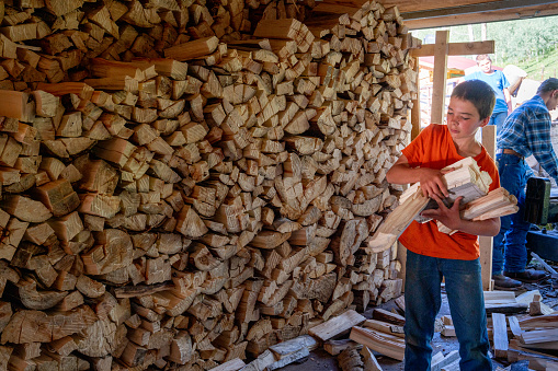 Industrial warehouse of a sawmill, an employee puts his hands on the finished products at the sawmill in the open air