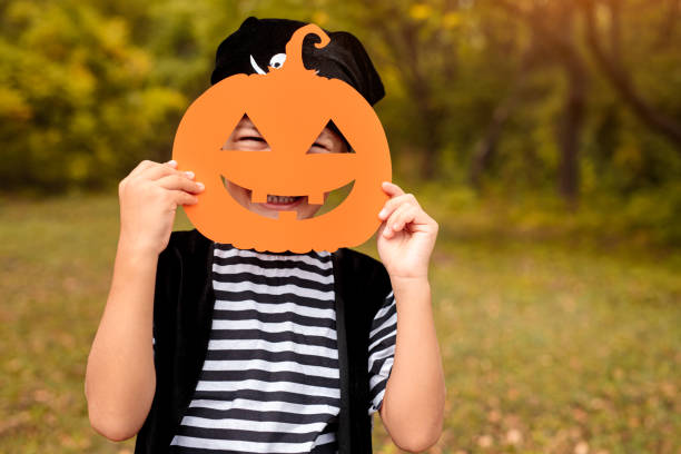 istock Funny kid standing with Halloween mask on nature background 1337722187
