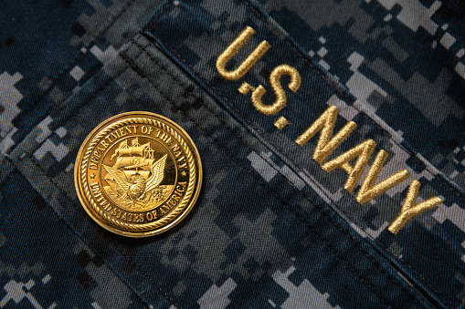 A US Navy gold coin on the Navy digital camo uniform background.