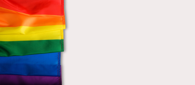 LGBT community flag on white background, banner with place for text, copy space. Top view part of rainbow flag symbol of freedom, equality and diversity.