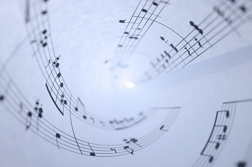 White paper with musical notes rolled up closeup background. Music writing concept