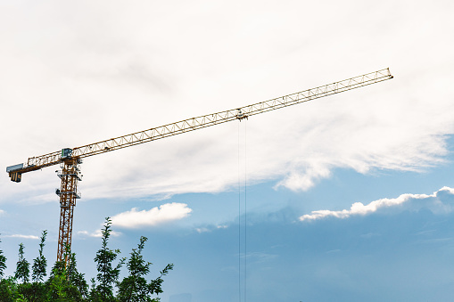 Tower crane working under white clouds