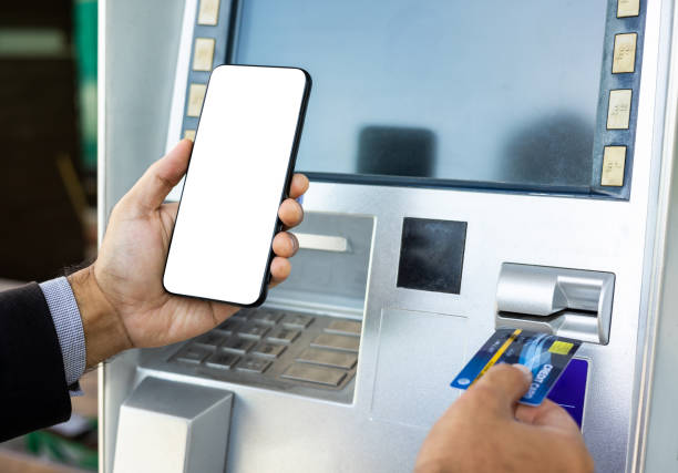 istock Young businessman standing front of atm machine using smartphone withdraw the money without atm credit card. He ut the pin code into smartphone and take the money. 1337752288